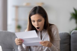 woman-with-shocked-expression-looking-at-a-bill